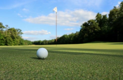 Single golf ball on a green with the hole and flag in the background