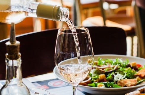 White wine being poured into a wine glass on a table at a restaurant