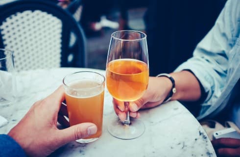 Two people sitting at a table each with a glass of beer