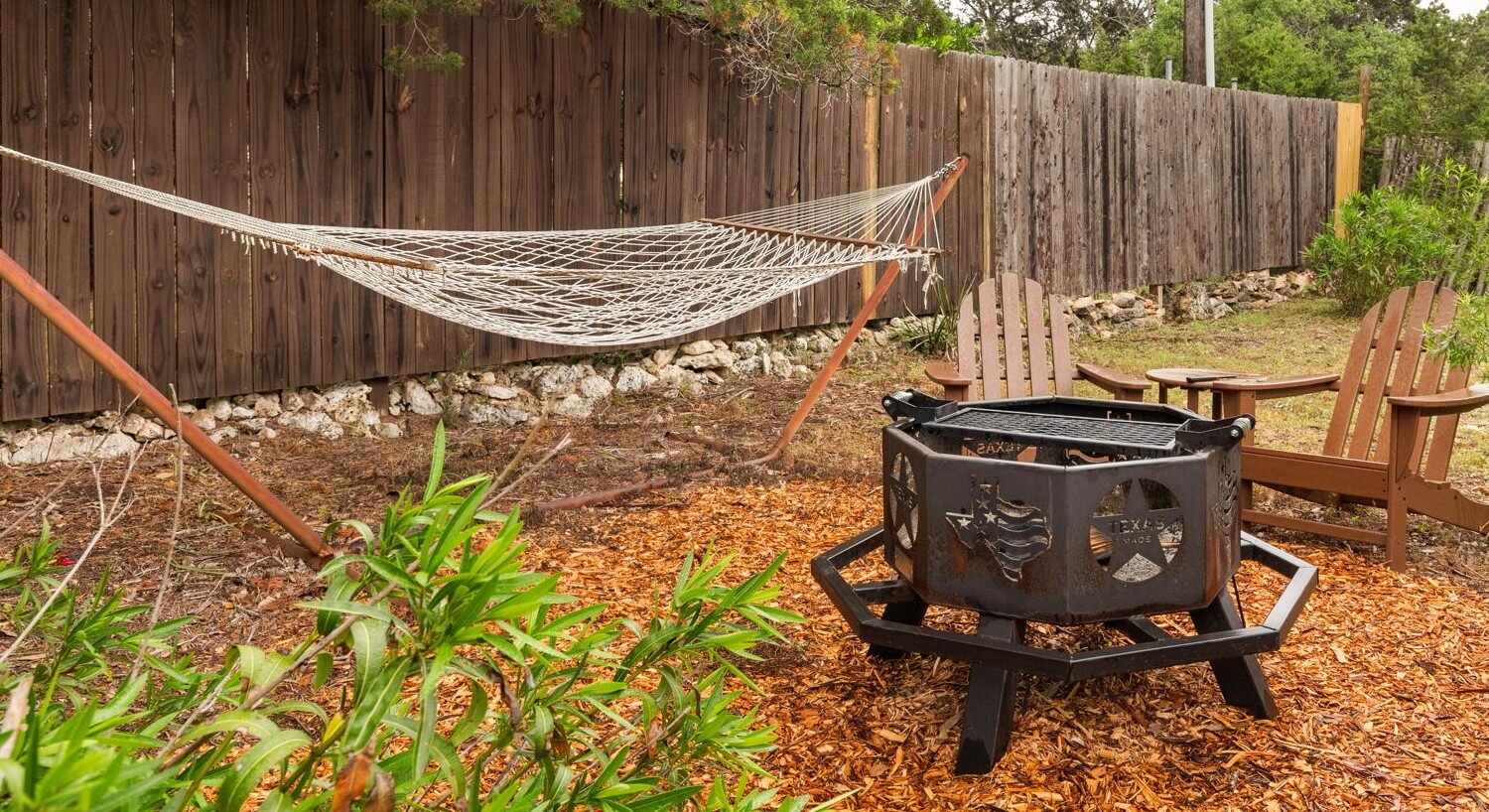 Outdoor area with a hammock, fire pit and two chairs.