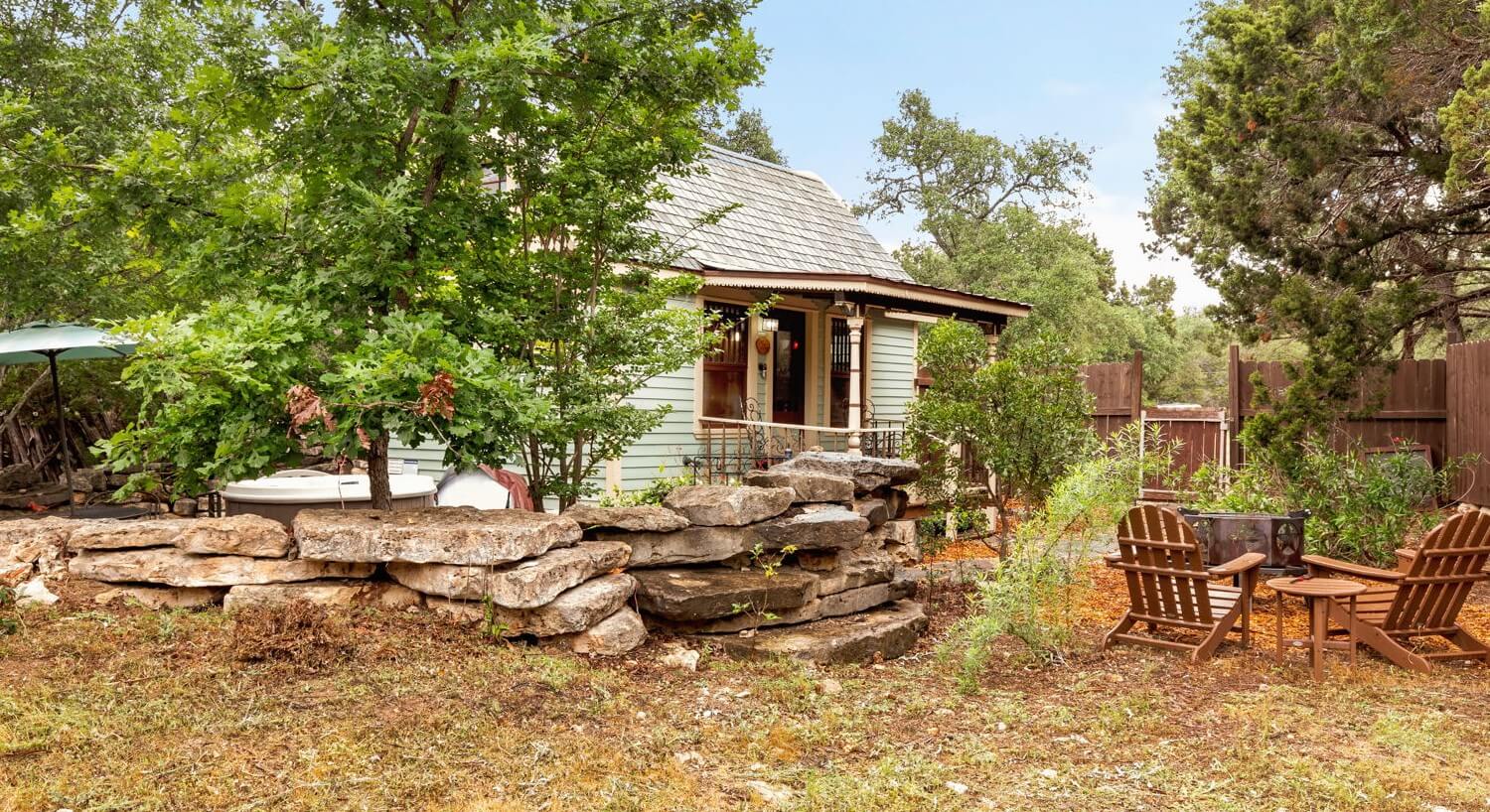 Outside of a tiny house with chairs and a rock wall.