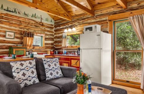 Interior of a log cabin with a kitchen and couch.