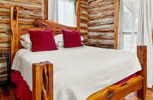 INterior of a log cabin with a queen size bed and windows.