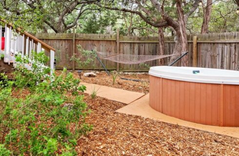 Fenced garden with a hammock and a hottub.