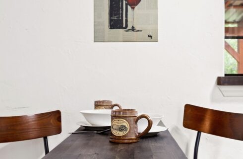 Wood table with two chairs and coffee mugs.