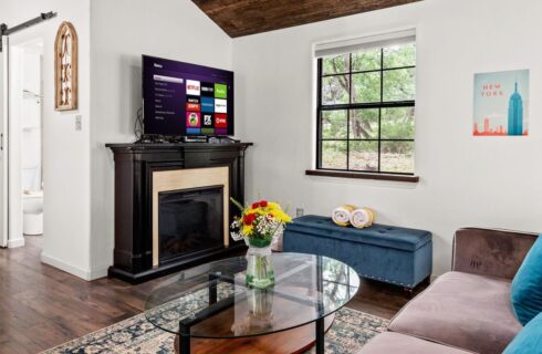 Interior of a cabin with spacious open floor plan, living room, glass coffee table and doorway into a bathroom