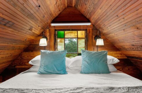 Loft area of a tiny house with wood ceiling and king bed.