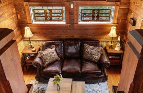 View from loft looking down onto living room with a leather couch.