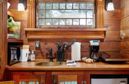 Small kitchen of a tiny house with wood counters and a sink.