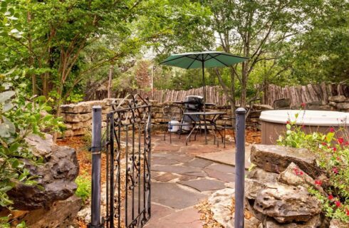 Small stone courtyard with a patio umbrella and hot tub.