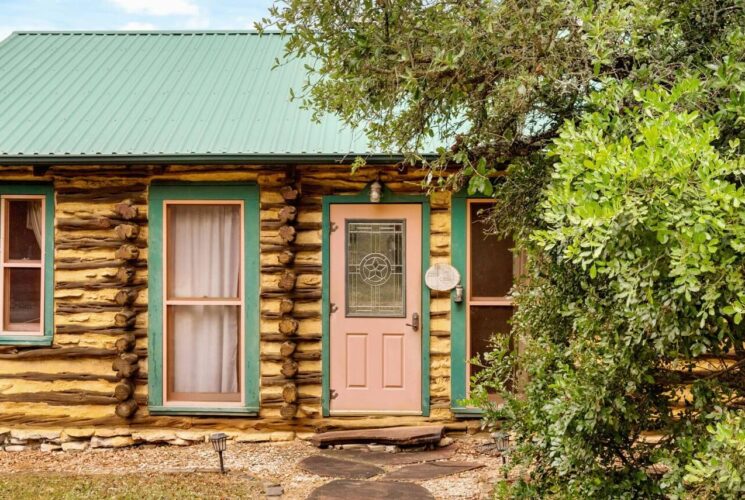 Log cabin with green roof nestled in the woods.