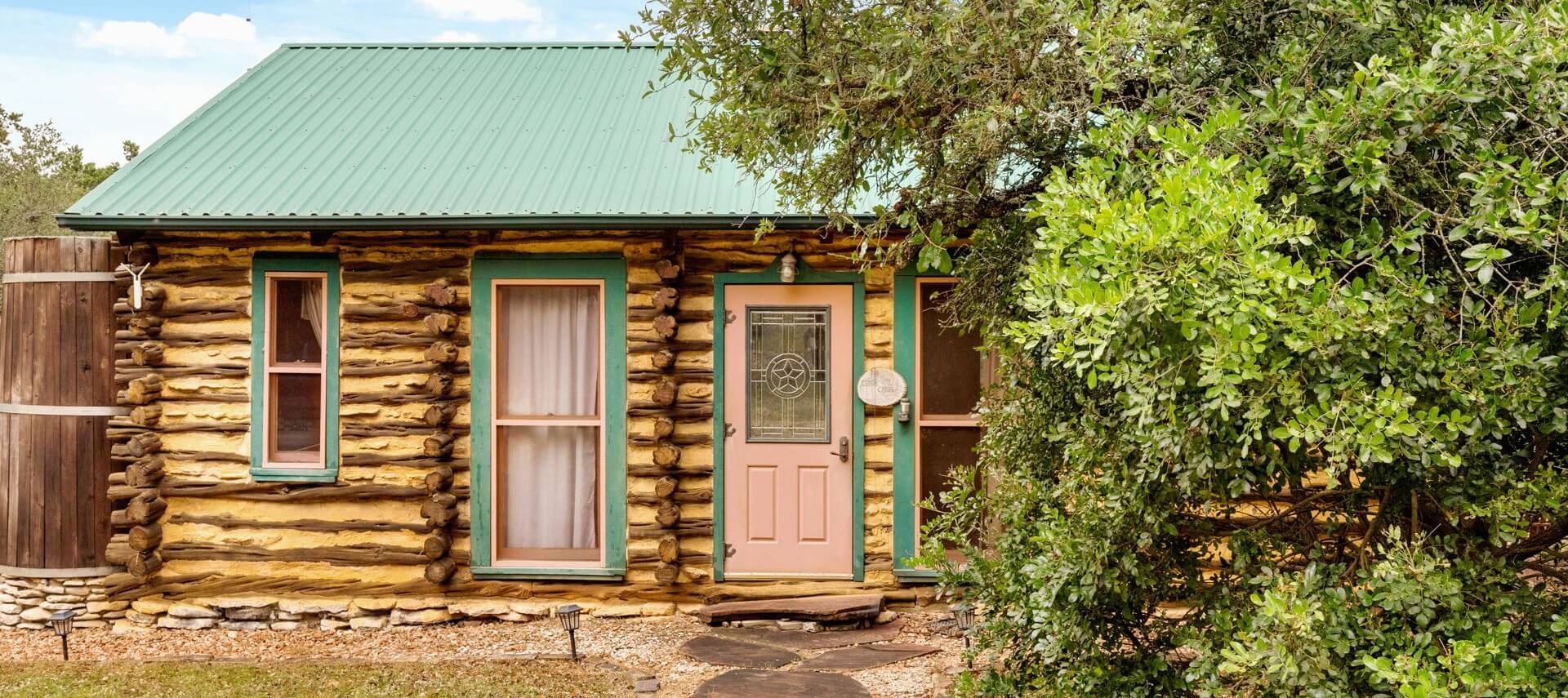 Log cabin with green roof nestled in the woods.