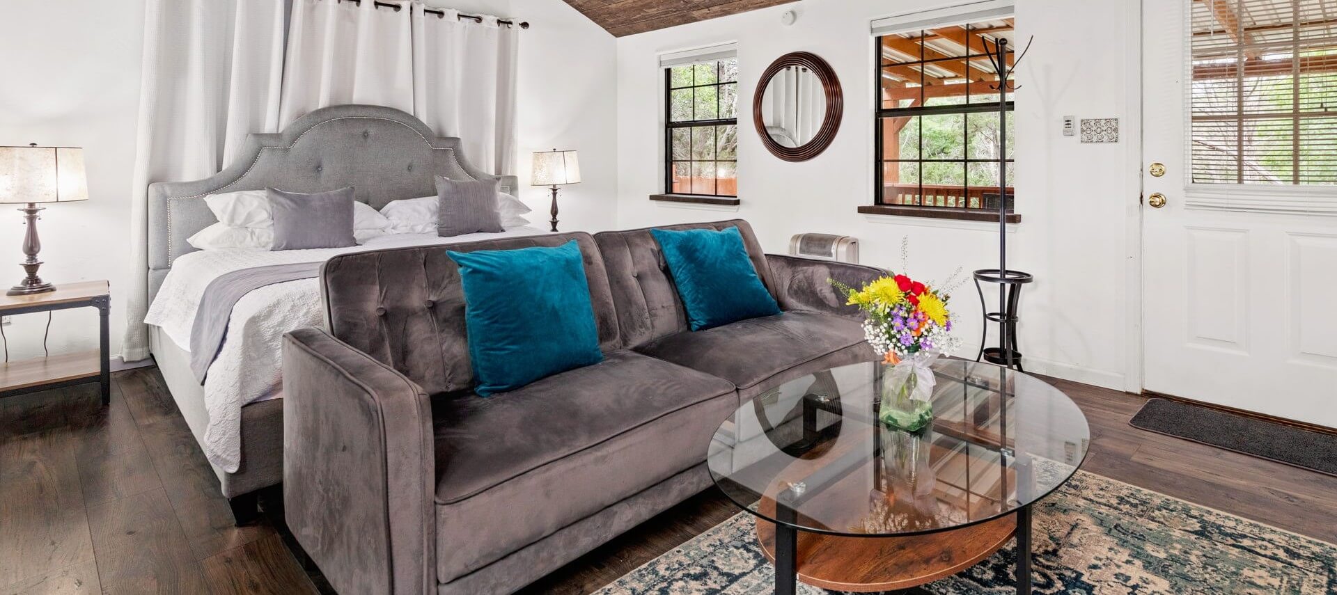 Interior of a spacious cabin with an open floor plan, king bed and living area flowing into a bar top table next to a bathroom