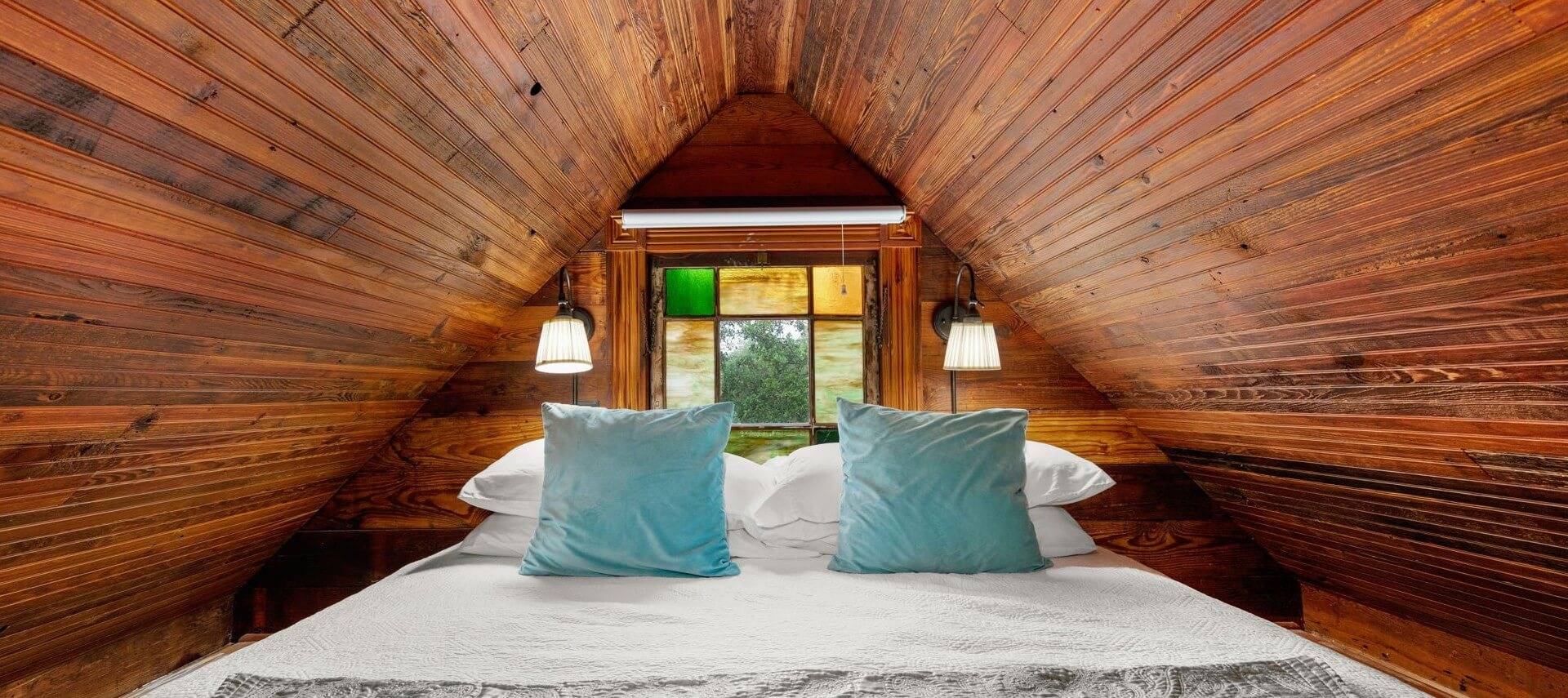 Loft area in a tiny house with a bed and wood ceiling.