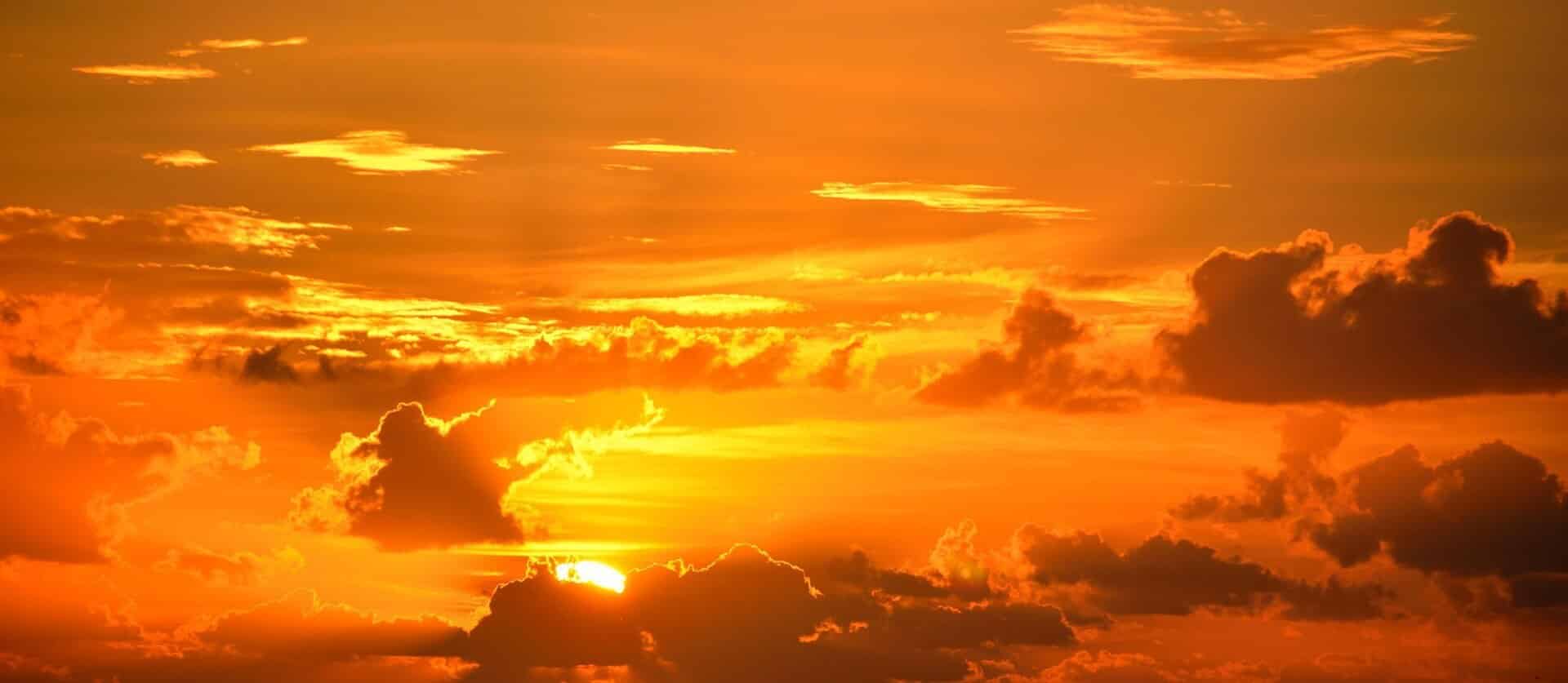 An image of a bright orange sunrise with clouds.